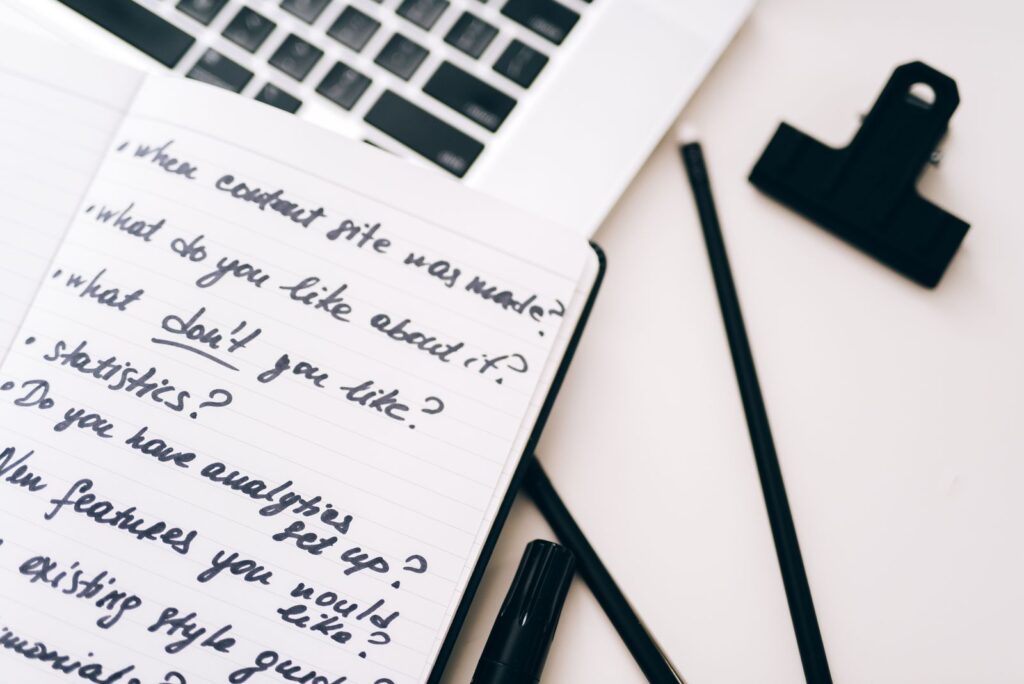 Notebook of handwritten notes beside a laptop, planning keywords and page titles for on-page SEO